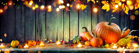 Thanksgiving - Pumpkins And Corncobs On Rustic Table With Garland And Defocused Abstract Lightsの写真素材