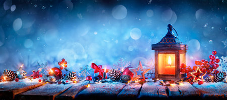 Christmas Lantern With Decorations and String Lights On Snowy Tableの写真素材