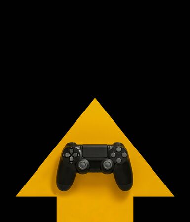 Modern black gamepad on a yellow arrow on a black background. Joystick on a yellow direction indicator on a dark background. Flat lay copyspace.の写真素材