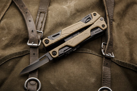 Modern multitool with many tools. A portable multitasking tool on a vintage canvas backpack. dark background.の写真素材
