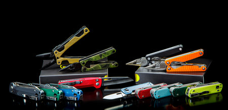 A variety of multi-tools and penknives lie on the table. Pocket tools for a variety of tasks. dark...