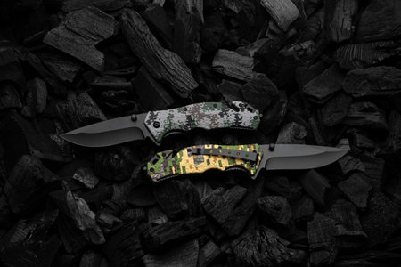 Modern knives with black blades. Hunting, military and folding knives on smoldering charcoal. Black background.の写真素材