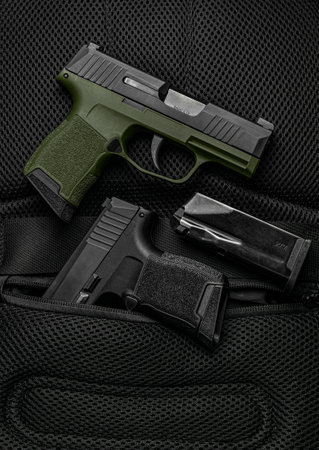 A small modern khaki semi-automatic pistols. A short-barreled weapon for self-defense. Arming the police, special units and the army. dark background.の写真素材