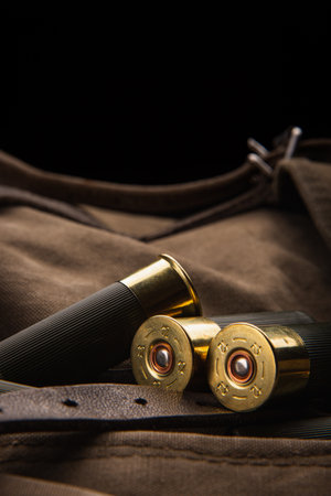 Shotgun shells close-up. Ammunition for smoothbore weapons on a khaki canvas backpack. dark background.の写真素材