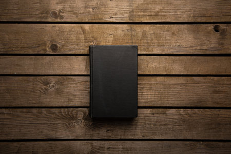 Closed book on vintage wooden background. Old book on the wooden table. Closed book with empty cover laying on wooden table.の写真素材