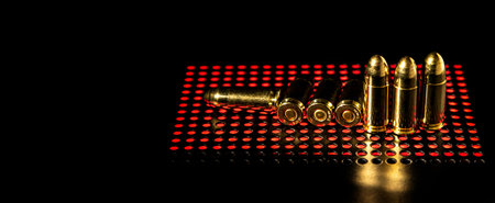 Pistol cartridges 9 mm on a smooth glossy surface with reflections. Ammunition for pistols and PCC carbines on a dark background.の写真素材