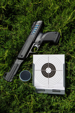 Air gun. Modern pneumatic weapon for air soft, sports and entertainment. A dummy, a copy of a real pistol. Pistol and target against a background of green fir.の写真素材