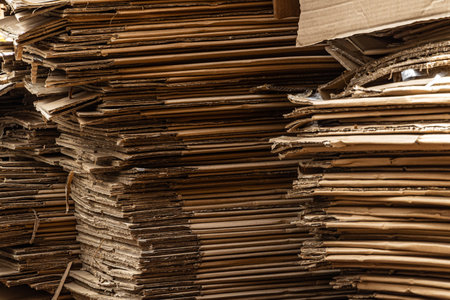 A vertical close-up of a large stack of cardboard boxes, showing the compressed layers and raw...