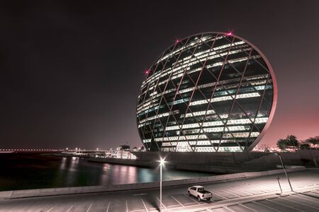 Aldar Headquarters Building, Abu Dhabi, United Arab Emirates - Oct.26, 2018: Modern round shape building overlooking the bay in the night lightsのeditorial素材