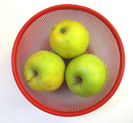 Three yellowgreen apples on red basketの写真素材