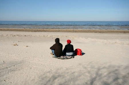 Woman and Man Sitting on Sand Watching Sea in Springの写真素材