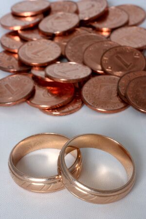 Two golden wedding rings and coins in the backgroundの写真素材