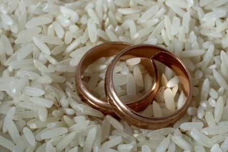 Two golden wedding rings on rice background