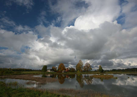 Lake and house under cloudsの写真素材