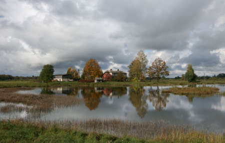 Lake and house under cloudsの写真素材