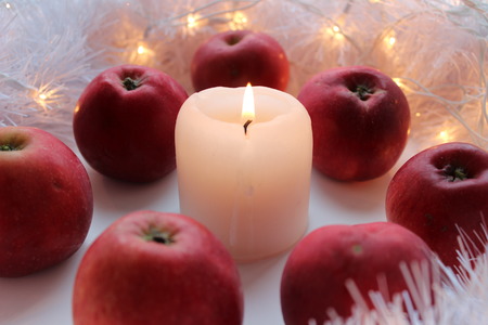 Christmas candle and decoration on white background, red apples aroundの写真素材