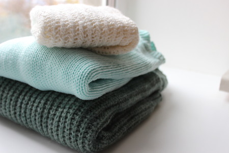three knitted sweaters neatly on a white backgroundの写真素材