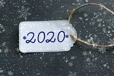 The price tag with the numbers 2020, the white tag against the black wood. The concept of the new...