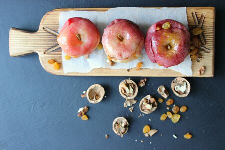 Baked red apples with cinnamon, walnuts and honey on a dark background. Autumn or winter dessert....
