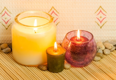 A closeup image of candles set on a bed of bamboo, used in aromatherapy in a spa の写真素材