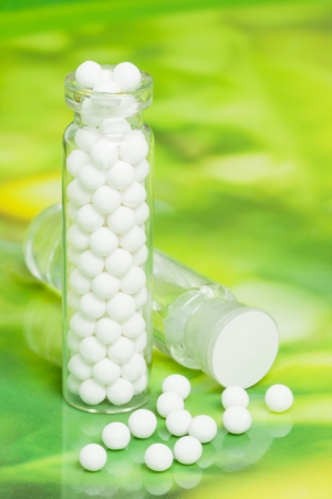 Macro image of homeopathic medicine consisting of the pills  made from an inert substance - sugar lactose  and a bottle containing a liquid homeopathic substance の写真素材