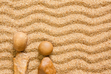 A wave patterned sand background with a silhouette of people set using beach stones symbolizing time spent at the beach in summer の写真素材
