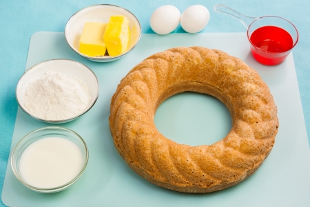 A delicious golden brown crusted pound bundt cake pictured along with its raw ingredients  The cake was baked in a ring shaped pan with fluted sides の写真素材