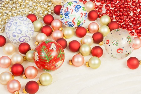 Christmas ornaments of different colors and sizes set in a random pattern along with red and gold colored beads on a silk clothの写真素材
