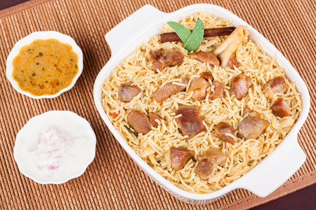 Overhead view from the top of delicious mutton (lamb) biryani with garnish and served with salad (raita) and gravy.の写真素材