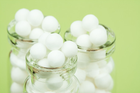 Homeopathic Pills  Macro closeup image of homeopathic medicinal pills made from an inert substance  sugarlactose in clear bottles on a green background.の写真素材