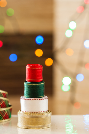 Christmas ribbon tree with lights bokeh - A Christmas tree made up of colorful decoration ribbon rolls stacked vertically on top of each other with multicolor bokeh by a set of de-focused lights.の写真素材