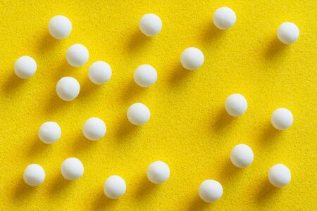 Homeopathic pills scattered - Overhead view of homeopathic pills made from inert substance - sugarlactose scattered on a yellow surface. Natural light used.の写真素材
