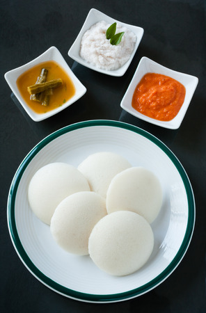 Indian idly with chutney and sambar - A traditional south Indian breakfast of fresh steamed Indian Idly Idli  rice cake served with tomato chutney, coconut chutney and sambar. Natural light used.の写真素材