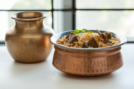 Mutton biryani - Closeup view of delicious mutton lamb biryani with mint garnish and served in authentic copper bowl. Natural light used.の写真素材