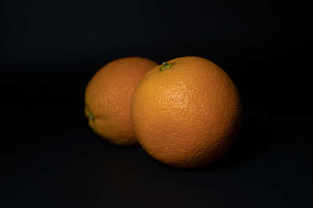 Two ripe oranges on a black background close-up.