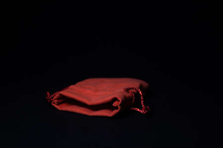 Red suede bag for costume jewelry on a black background.の写真素材