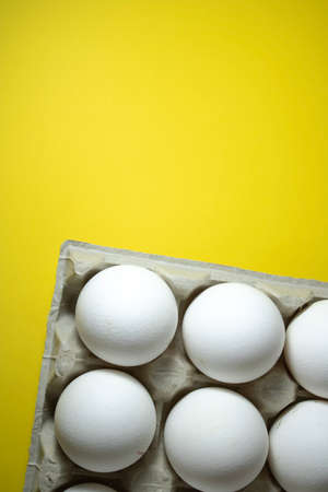 Chicken eggs in paper packaging on a yellow background.の写真素材