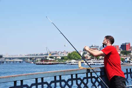 An unknown fisherman catches fish from the bridge. A man is fishing in Istanbul from the Galata Bridge. Fishing. July 10, 2021 Istanbul, Turkeyのeditorial素材