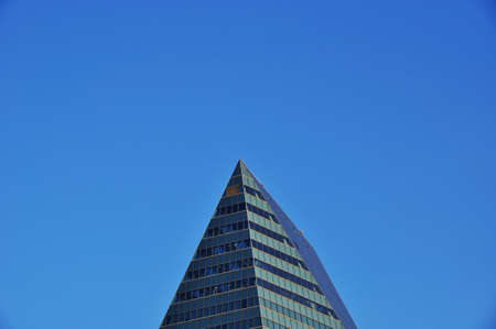 The upper floors of a skyscraper against a cloudless blue sky. Summer sunny day.