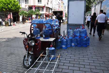 Delivery of clean drinking water in bottles. Delivery of bottled water by motor scooter. July 08, 2021, Istanbul, Turkey.のeditorial素材