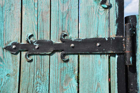 Forged metal hinges of an old wooden door. Background, texture, design.