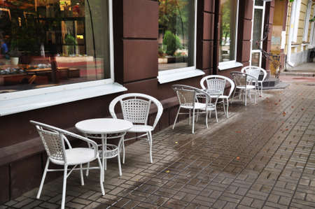 A row of white tables and chairs along the house. Summer cafe tables. September 02, 2021, Orel, Russia.のeditorial素材