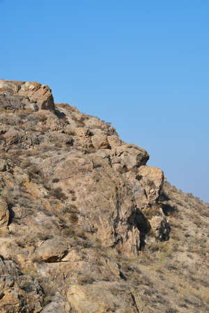 Panoramic view of the gentle slope of the mountain. Mountain without vegetation against the blue sky.の写真素材