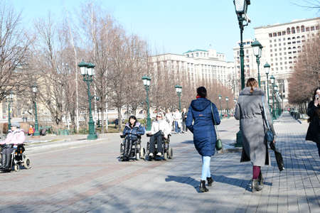 People walk in Alexander Park in Moscow. People with limited mobility in wheelchairs. 03.24. 2022 Moscow, Russia.のeditorial素材