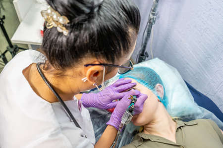 Beautiful woman making permanent makeup in cosmetology salon.