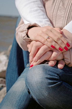 Loving couple holding hands with weddind ring and red nailsの写真素材