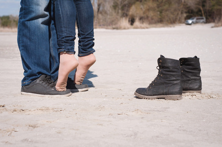 Loving couple on the beach in jeans and black shoesの写真素材