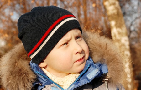 Photo of pretty boy face in warm clothing at the autumn park