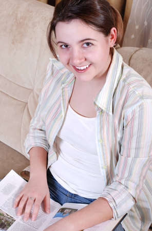 Closeup portrait of smiling teenage girl reading the bookの写真素材