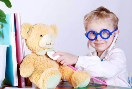 Little doctor  takes a patient - his teddy bear toyの写真素材
